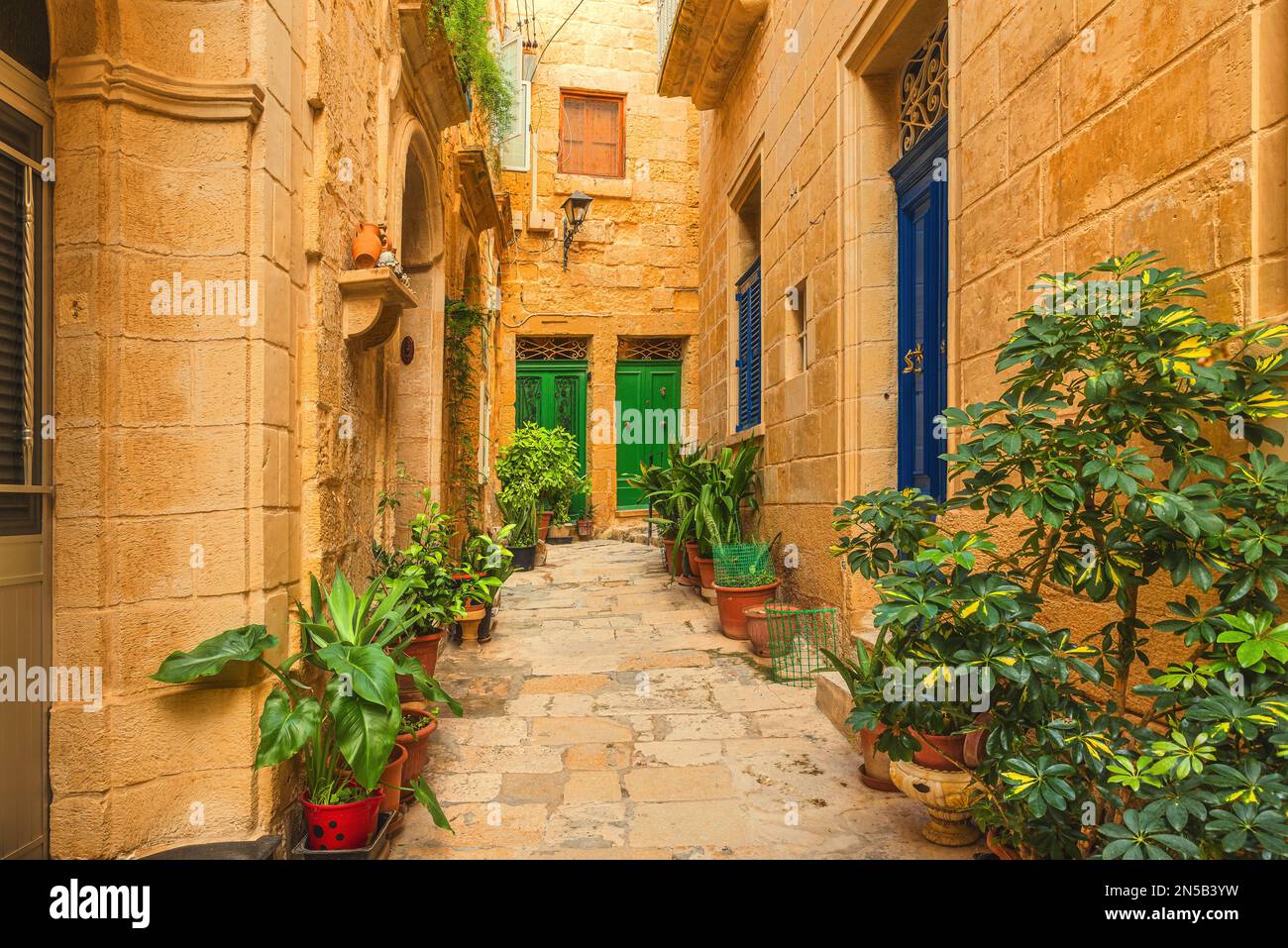 flower-pots-in-the-old-medieval-narrow-street-with-yellow-stone
