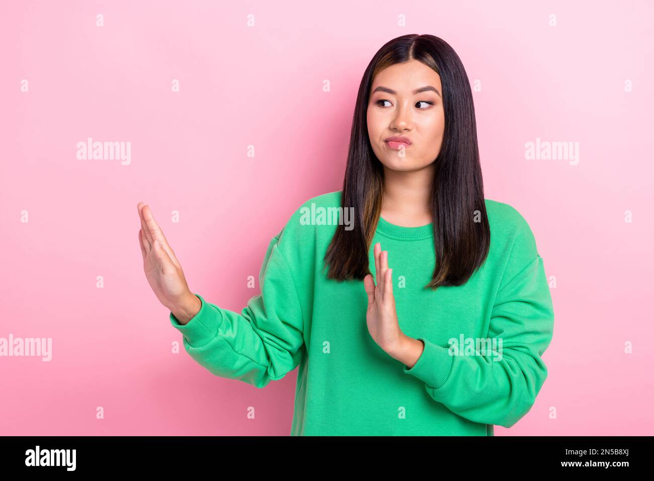 Photo of serious spoiled girl dressed green sweatshirt showing arms no empty space isolated pink color background Stock Photo