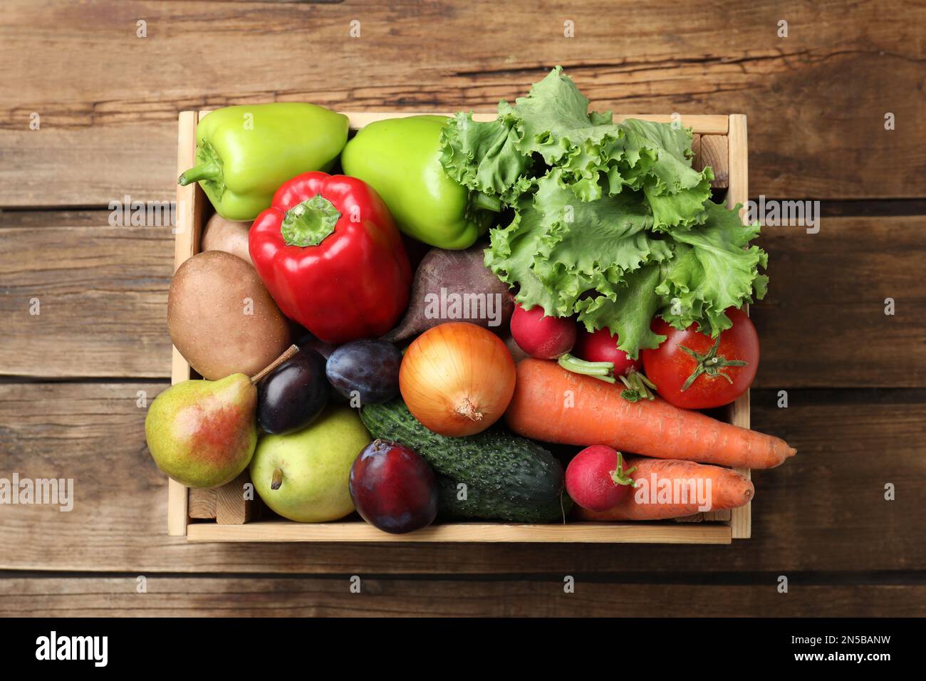 Crate full of different vegetables and fruits on wooden table, top view ...