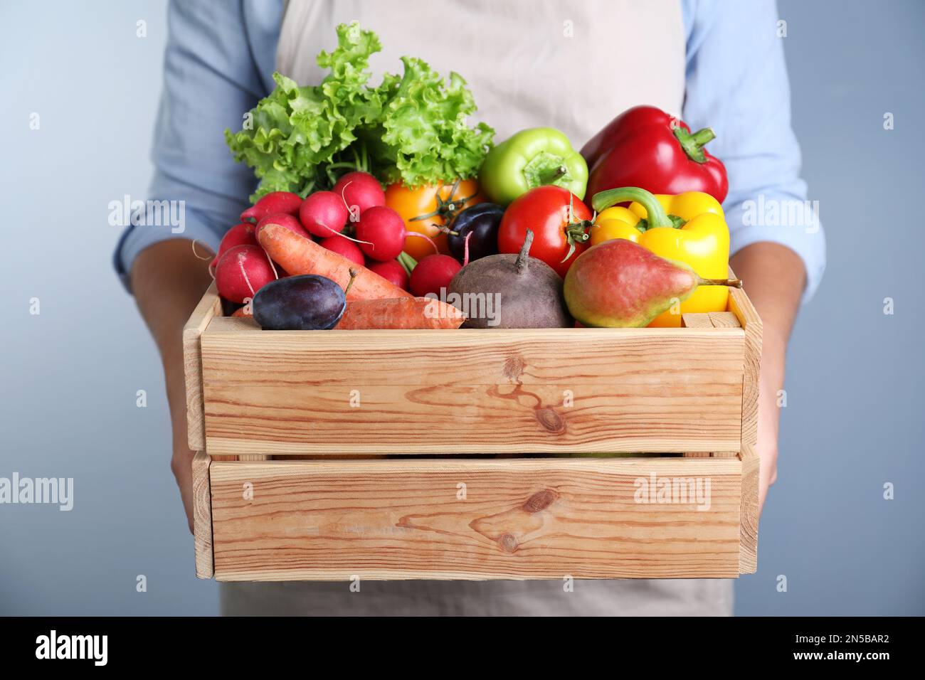 Farmer with wooden crate full of different vegetables and fruits on ...