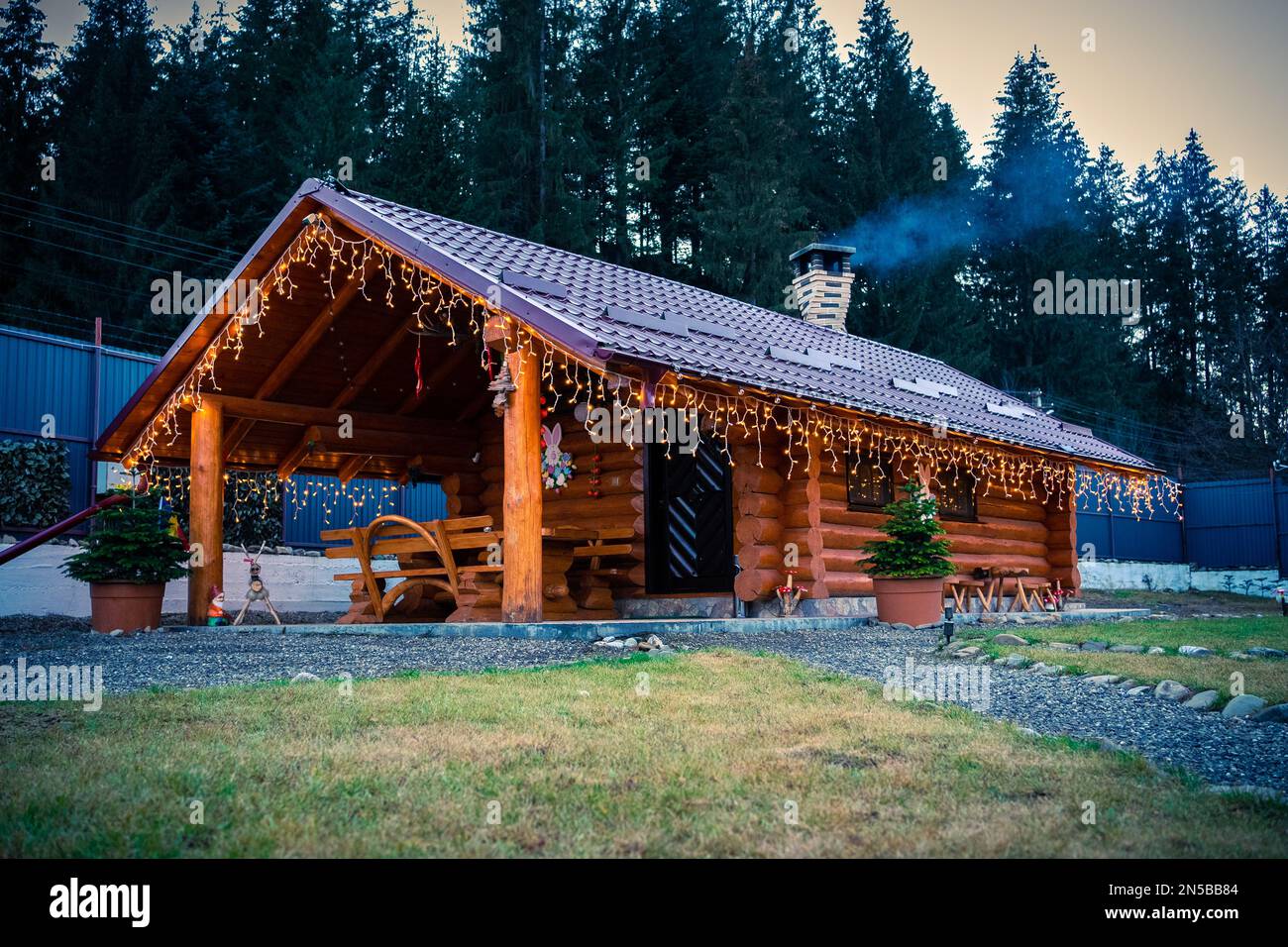 Wooden Cabin from Bucovina region of Romania. European spruce forest background and fireplace burning inside Stock Photo
