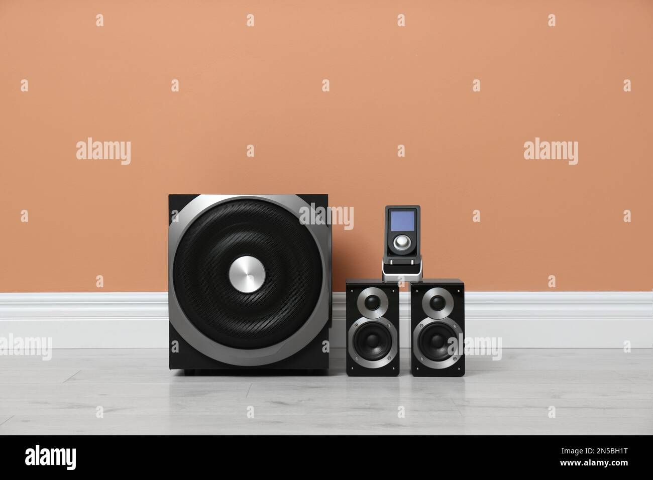 Modern powerful audio speaker system on floor near orange wall Stock