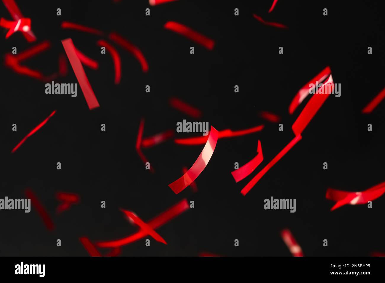 Shiny red confetti falling down on black background Stock Photo Alamy