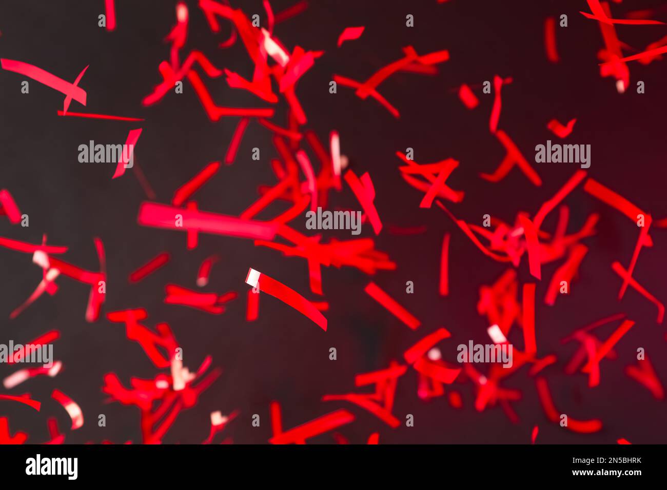 Shiny red confetti falling down on dark background Stock Photo Alamy