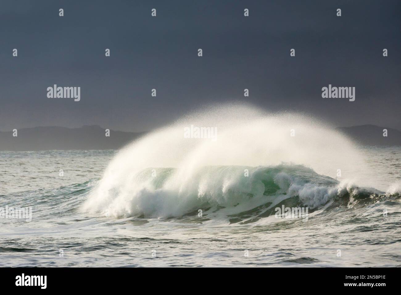 big wave breaking in winter storm in open sea and dramatic light off north coast of Ireland, Ireland, County Donegal, Fintra Beach Stock Photo
