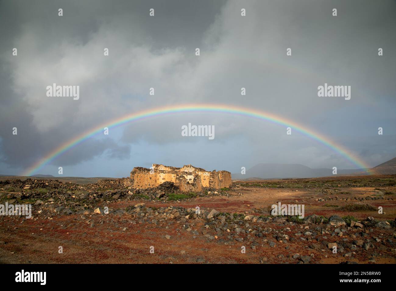 rainbow over dilapidated finca in the semi-desert, Canary Islands, Lanzarote, Guatiza Stock Photo