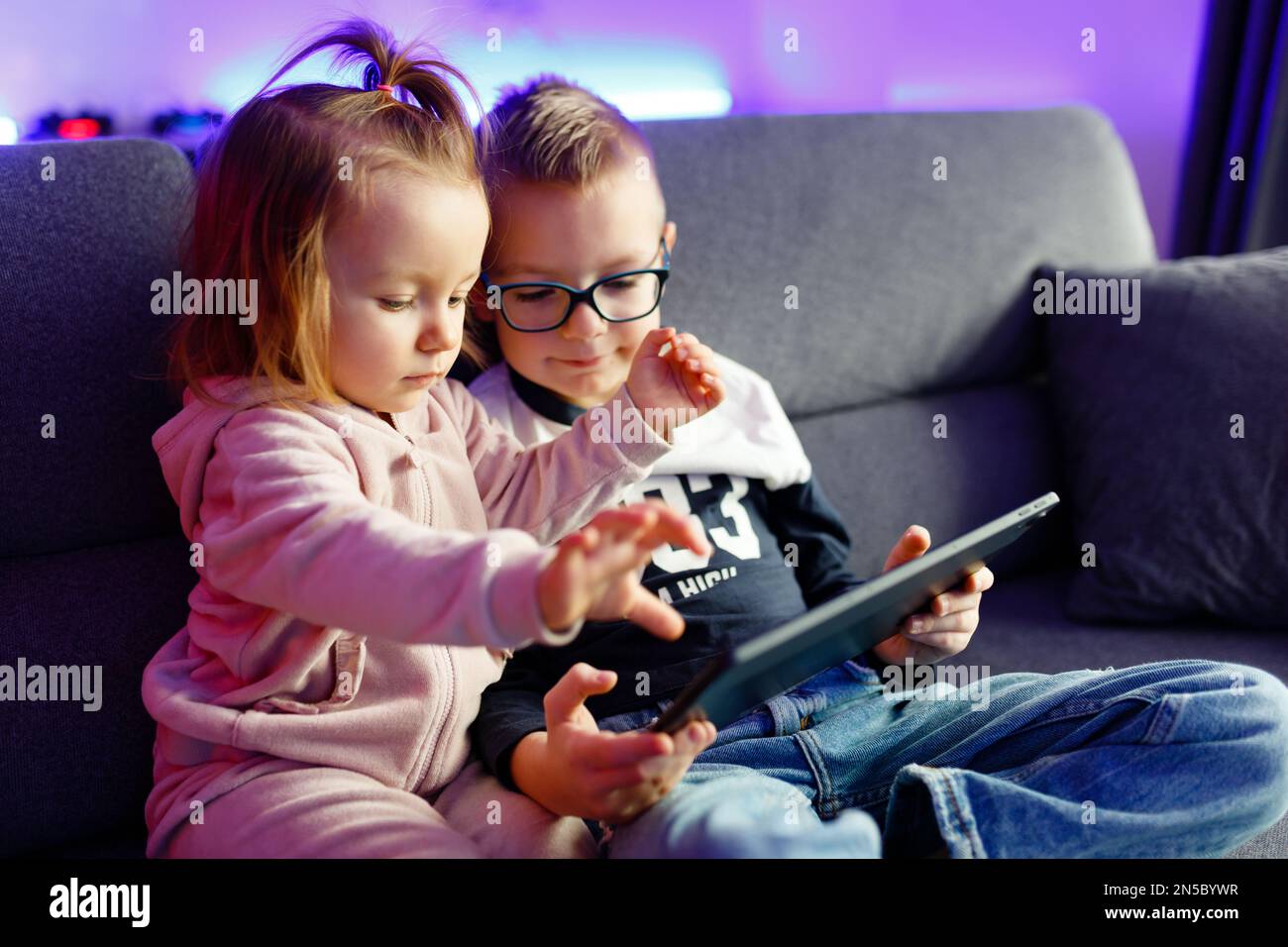 Danya's older brother teaches her younger sister how to use a tablet ...
