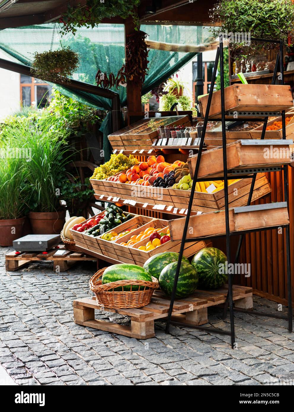 Fruit stand at a street market outside with organic watermelons, oranges, lemons in wooden crates small business vegan healthy food Stock Photo