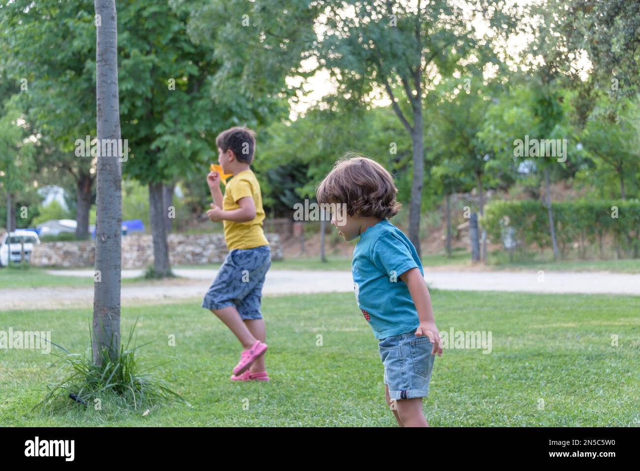 Two little kids playing with cardboard toy airplane in the park at the