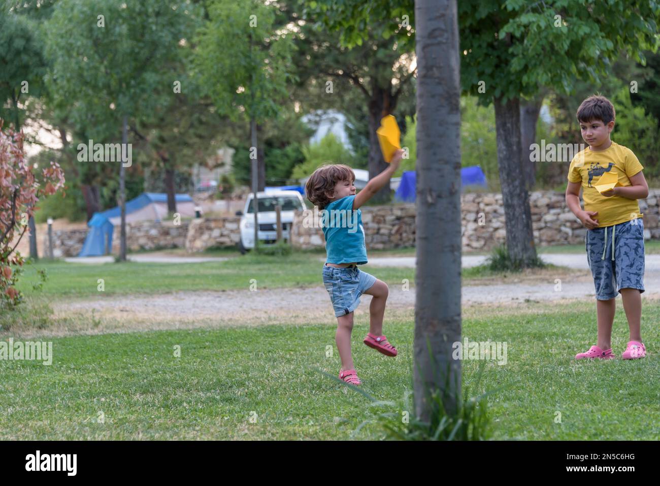 Two little kids playing with cardboard toy airplane in the park at the ...