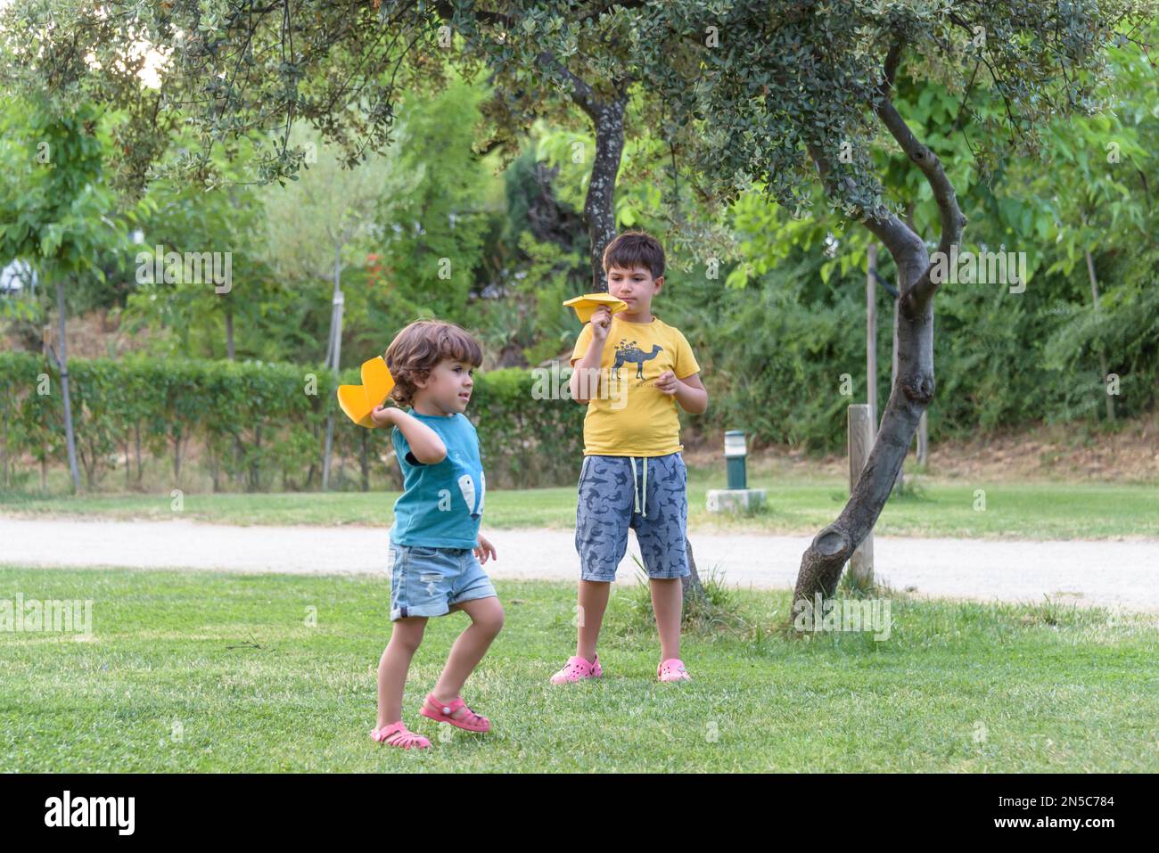 Two little kids playing with cardboard toy airplane in the park at the ...