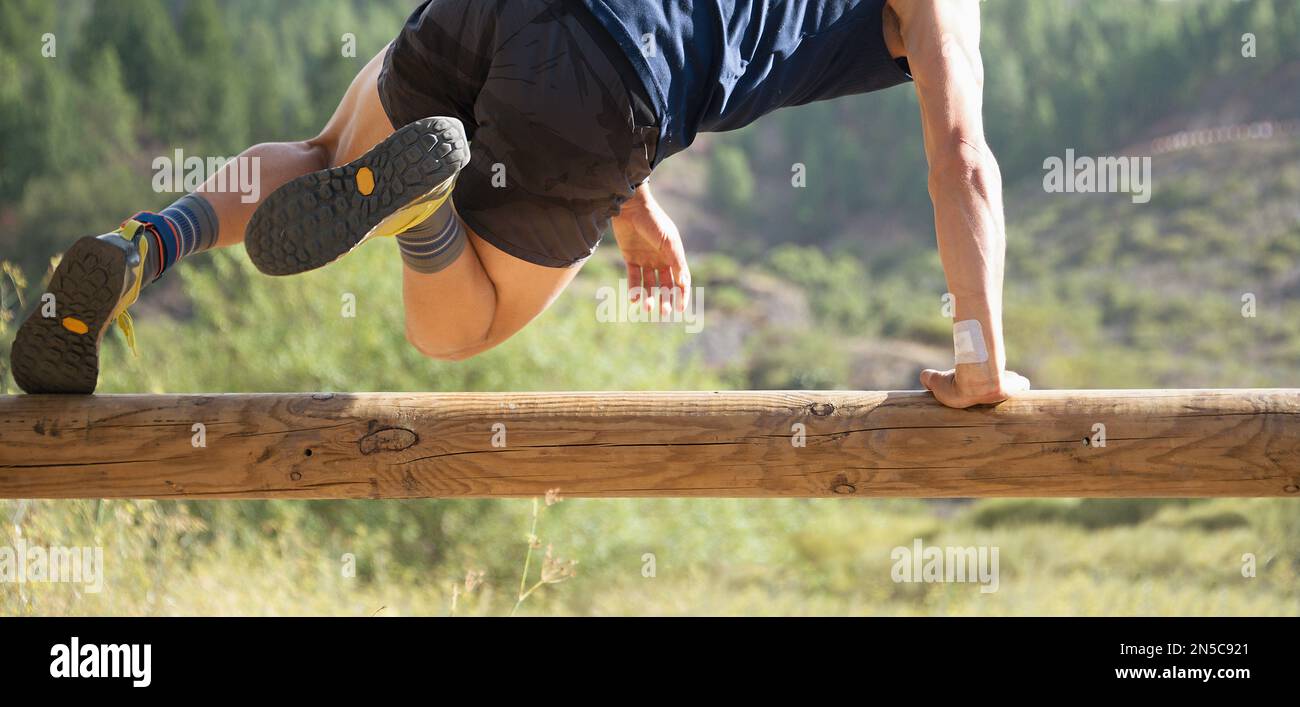 Participant in an obstacle course running, jump over wooden log