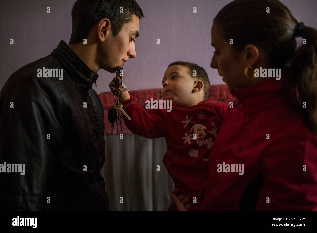 Jonathan Diaz, left, looks at his baby holding the house's keys next to