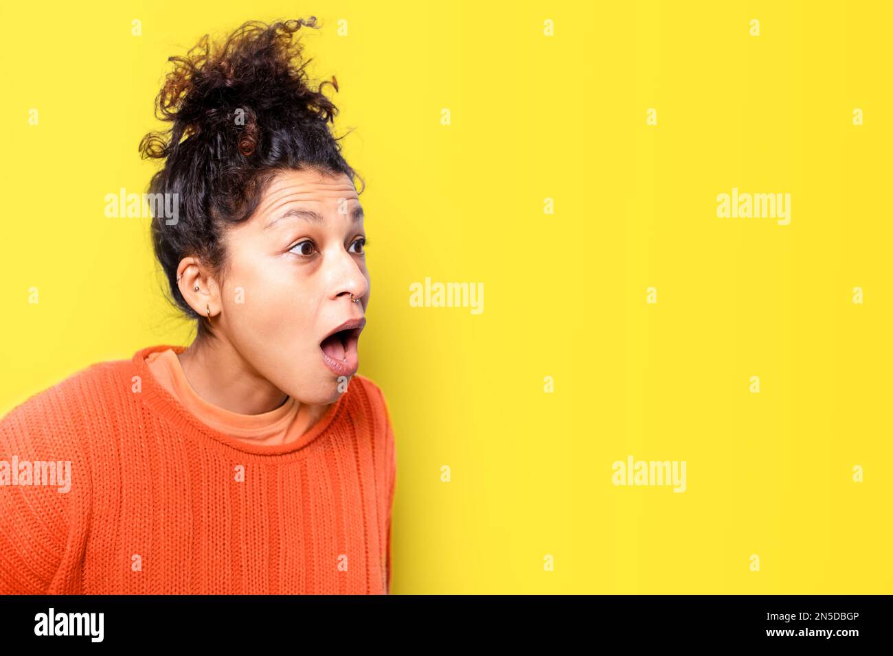 Amazed and astonished face expression on yellow background Stock Photo