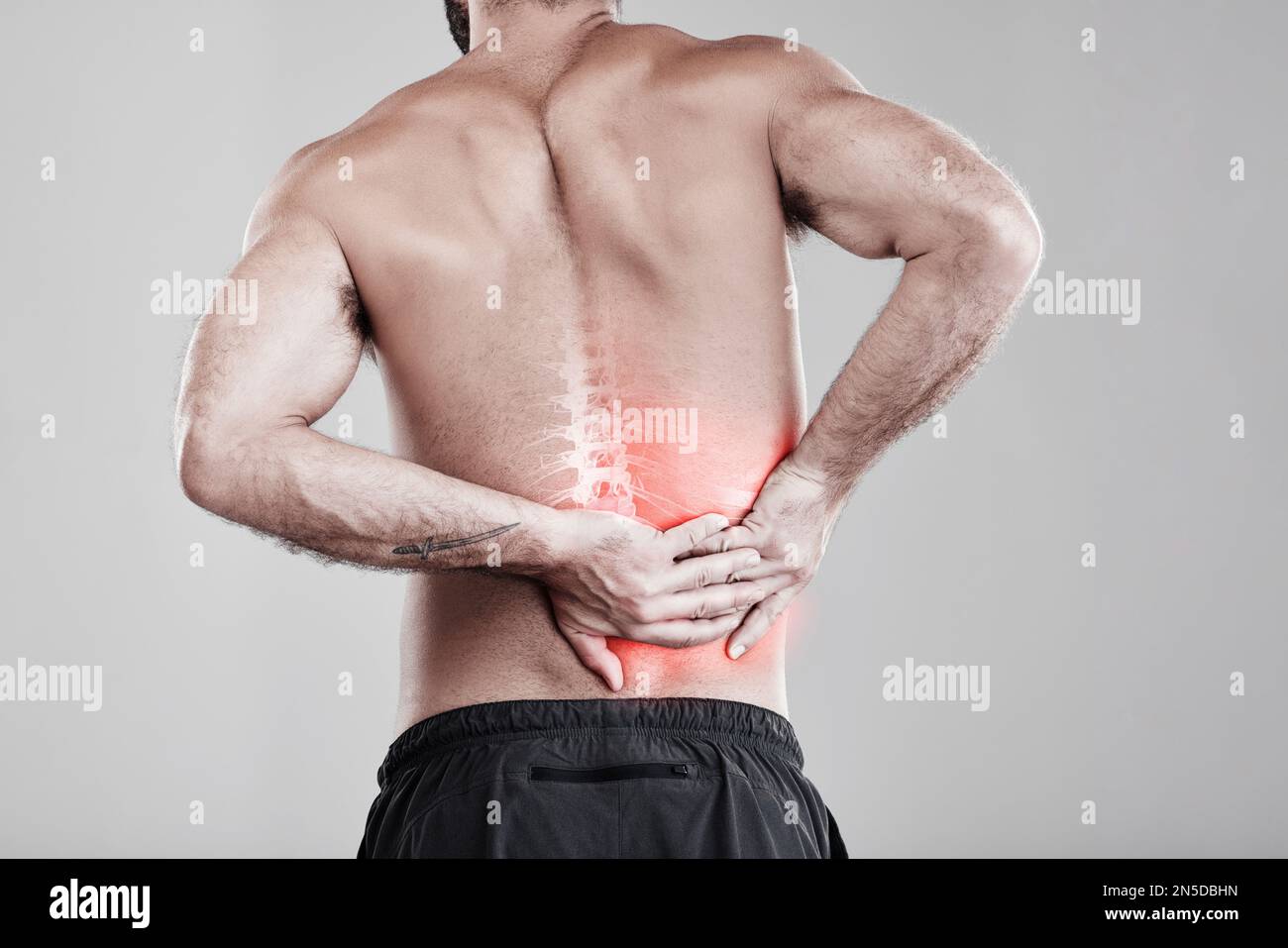 Man, hands and back pain in x ray for injury, bruise or spinal ache against a gray studio background. Male model suffering from broken spine Stock Photo