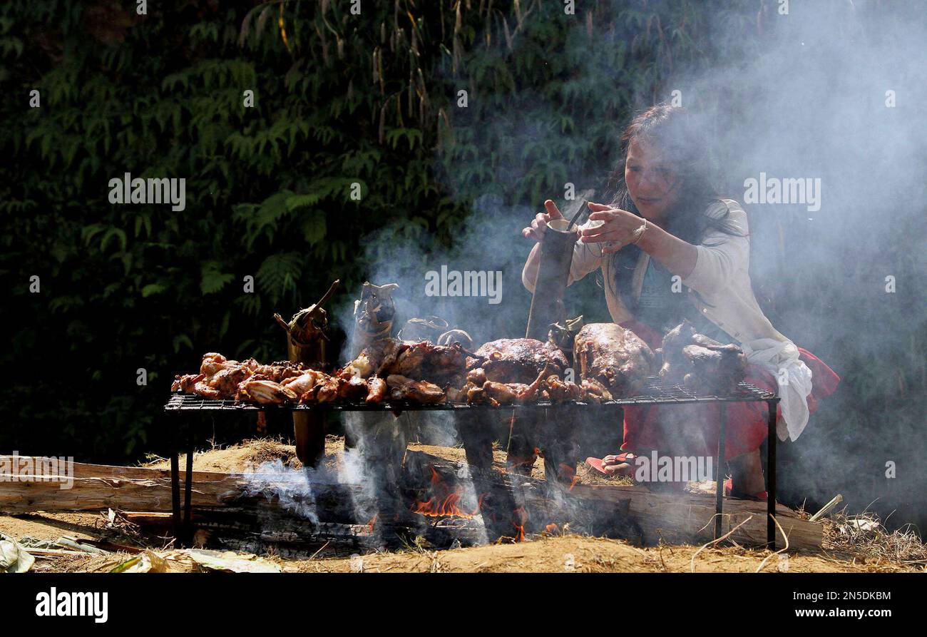 A Nishi tribal woman roasts meat during the 28th statehood day