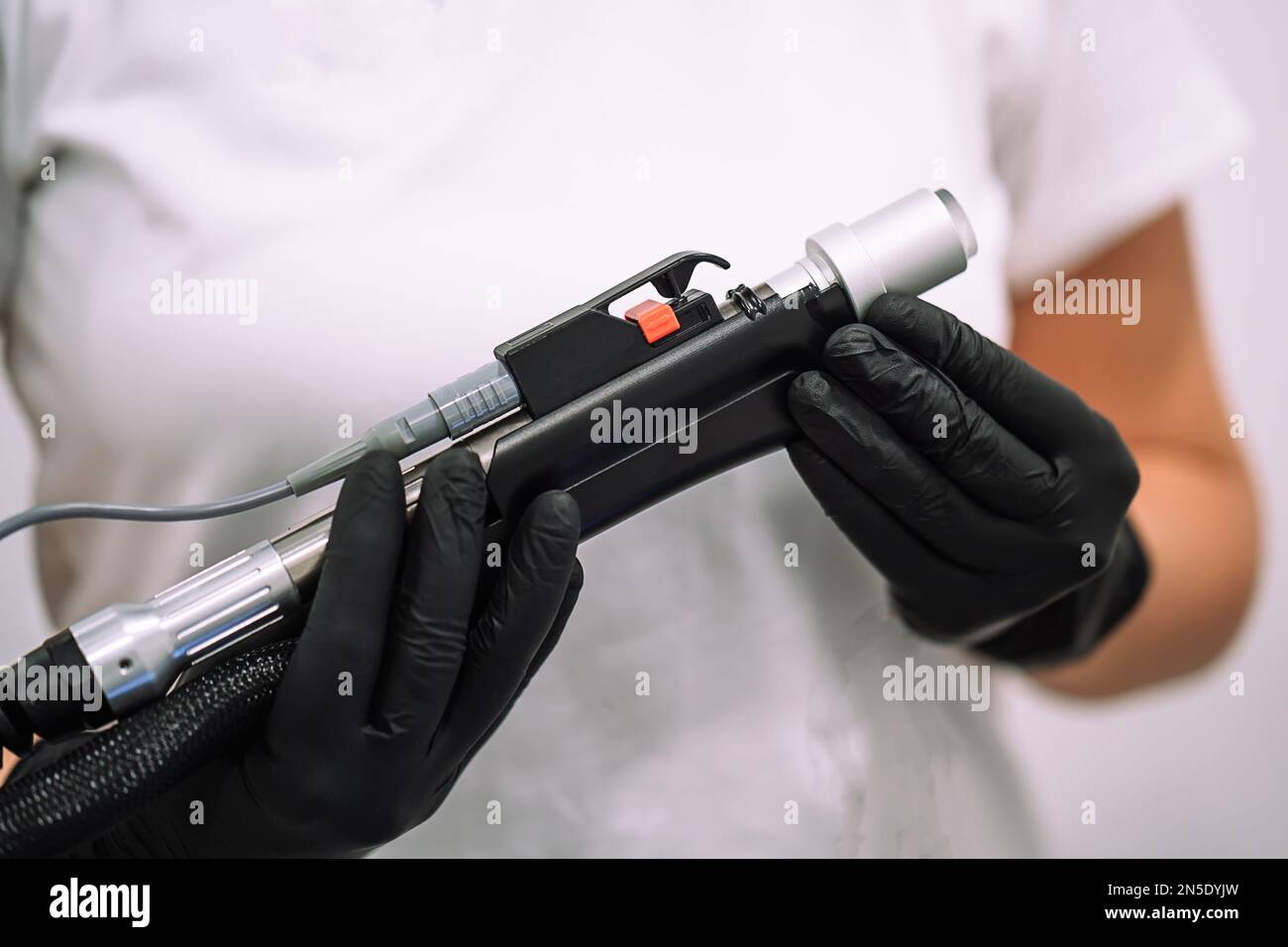 Close up shot of gloved hand with the laser hair removal machine's handpiece. Alexandrite laser techhnology removing hair. Beauty technology concept Stock Photo