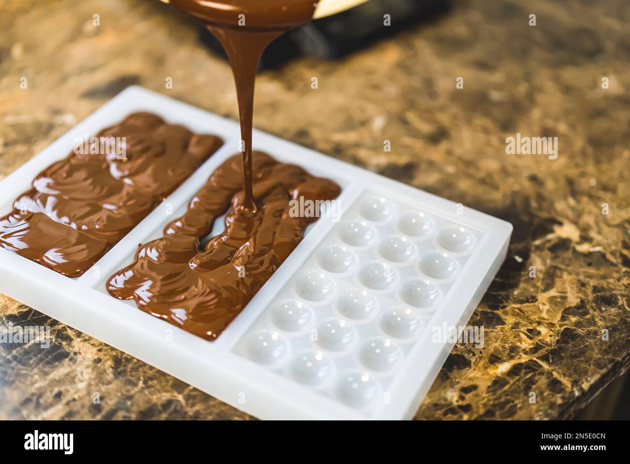 Craft chocolate liquid being poured into a bar silicone mold to cool down. High quality photo Stock Photo