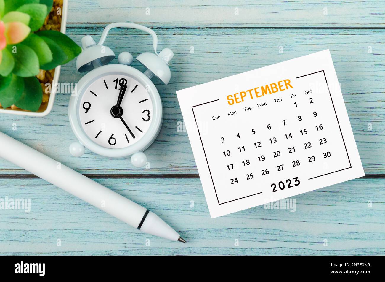 September 2023 Monthly calendar year and alarm clock with pen on blue ...