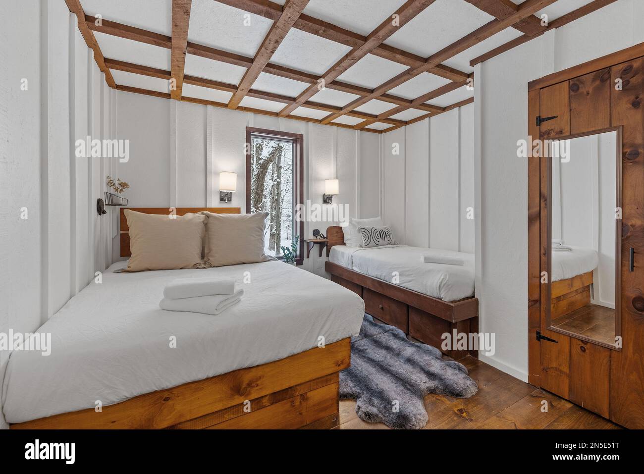 A king size bed and small bed in a white bedroom next to each other Stock Photo