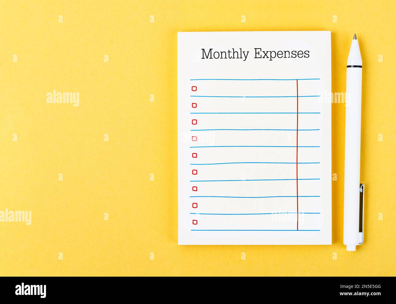 Blank Monthly expenses planning checklist with pen on yellow background. For your text. Stock Photo