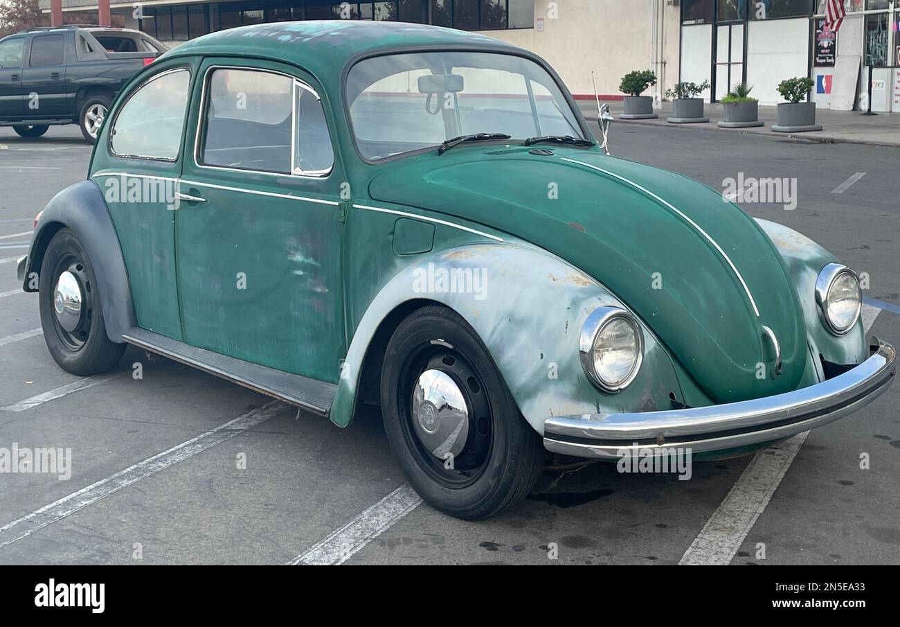 An old retro green and white Volkswagen Bug in the parking lot during the daytime Stock Photo