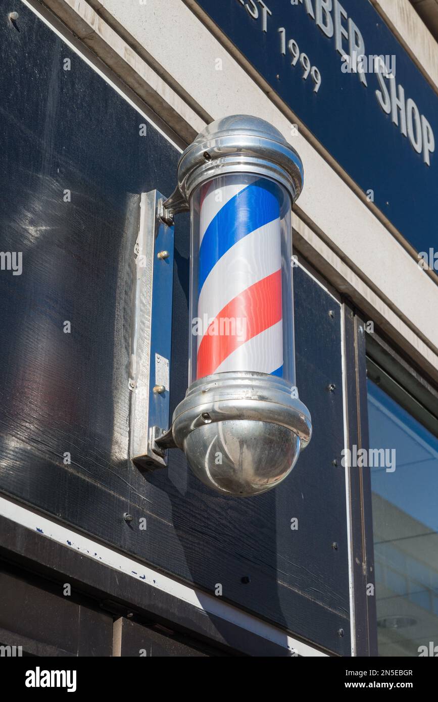 Traditional blue, red and white rotating cylinder sign outside barbers shop Stock Photo