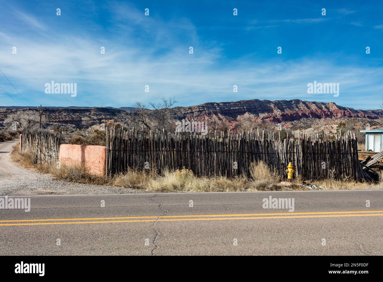 Vintage wooden pole fence in front of an old house in rural New Mexico Stock Photo