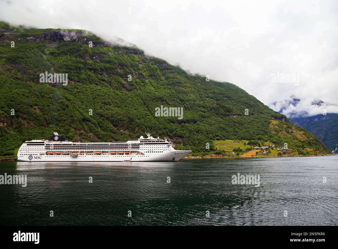 GEIRANGER, NORWAY - JULY 6, 2016: The liner MSC Opera is at anchor in Geiranger Fjord near the town of Geiranger. Stock Photo
