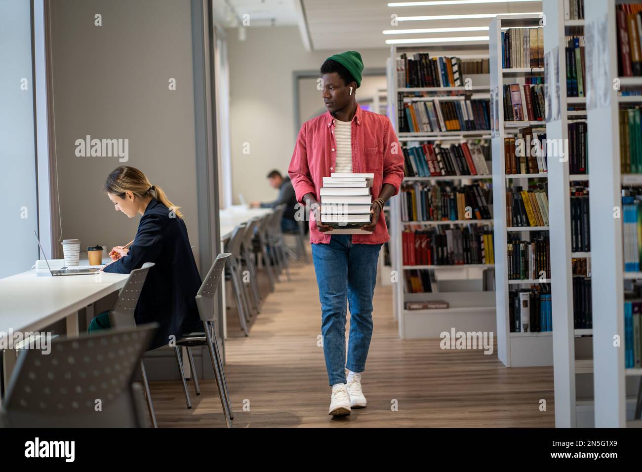Library Guy African American international student guy walking with stacked books ...
