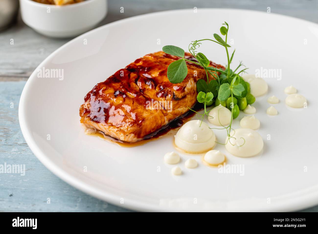 Grilled salmon fillet with sauces next to it on a white porcelain plate