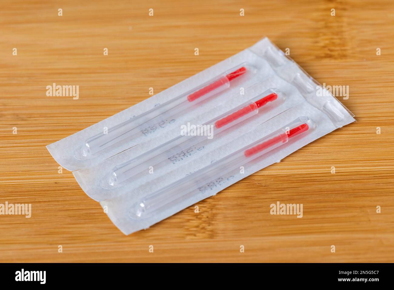 A closeup portrait of long tin single wrapped acupuncture needles still in the package, ready to use on someone with health issues. There is also a tu Stock Photo