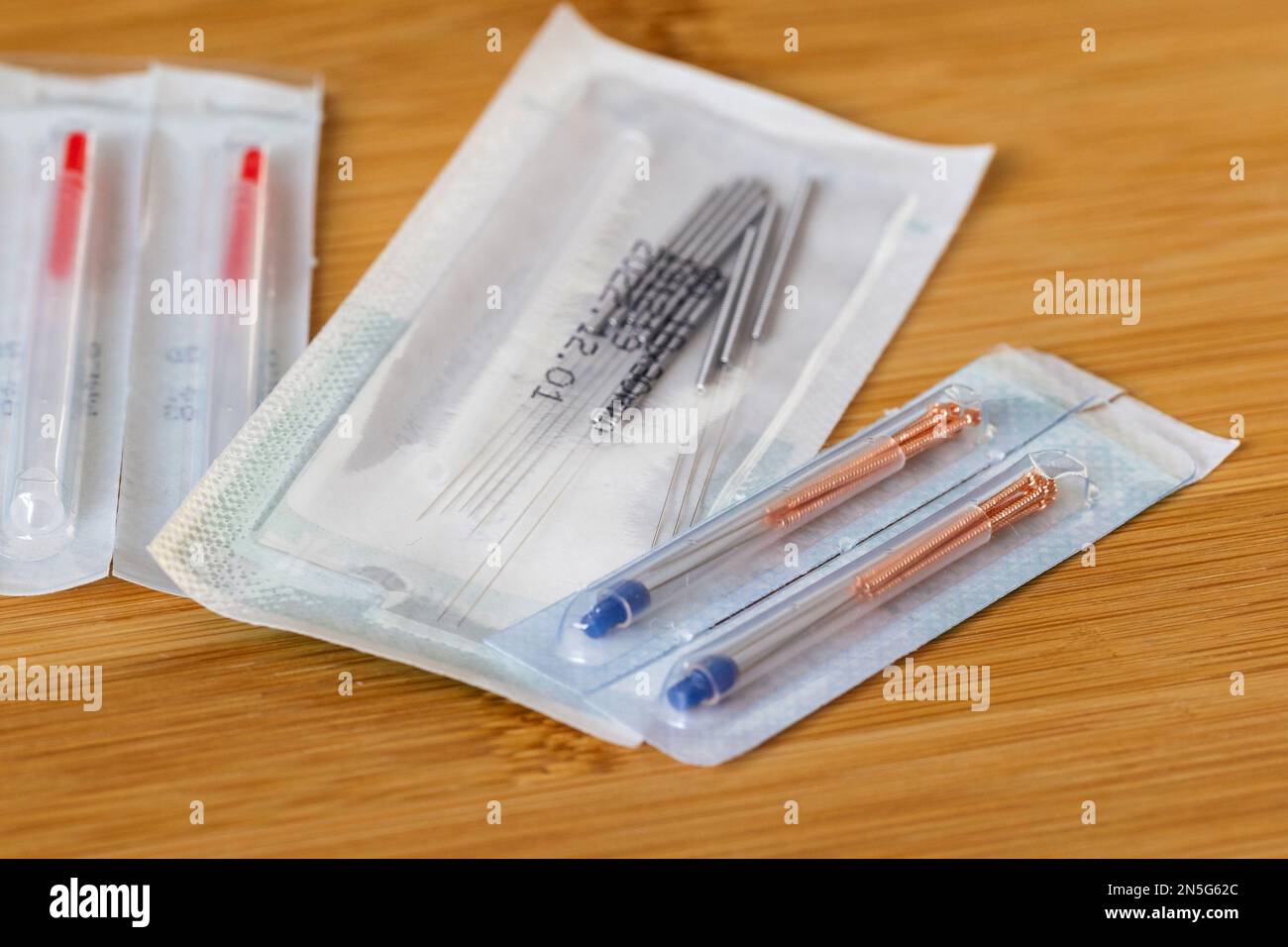 A close up portrait of multiple packages of different acupuncture needles, ready to use on someone with health issues. There are also plastic tubes in Stock Photo
