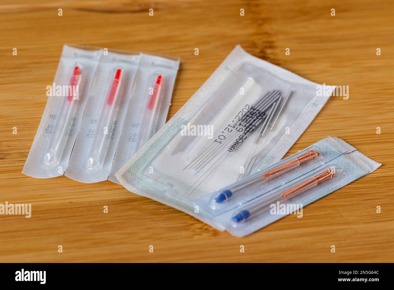 A portrait of multiple packages of different acupuncture needles, ready to use on someone with health issues. There are also plastic tubes inside in o Stock Photo