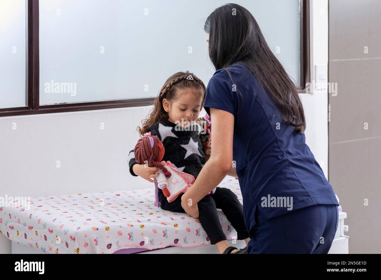 Doctor seating a girl on a medical examination table, with copy space ...