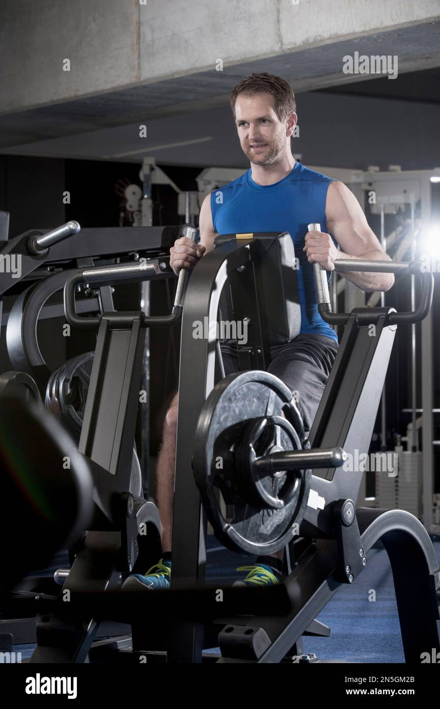 Mid adult man doing exercise on machine in the gym, Bavaria, Germany Stock Photo