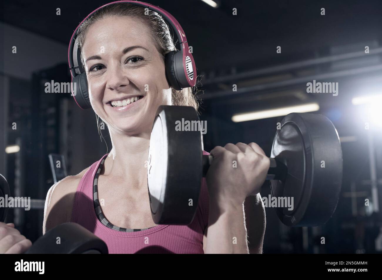Portrait of a mid adult woman doing exercise with dumbbells in the gym and listening to music, Bavaria, Germany Stock Photo