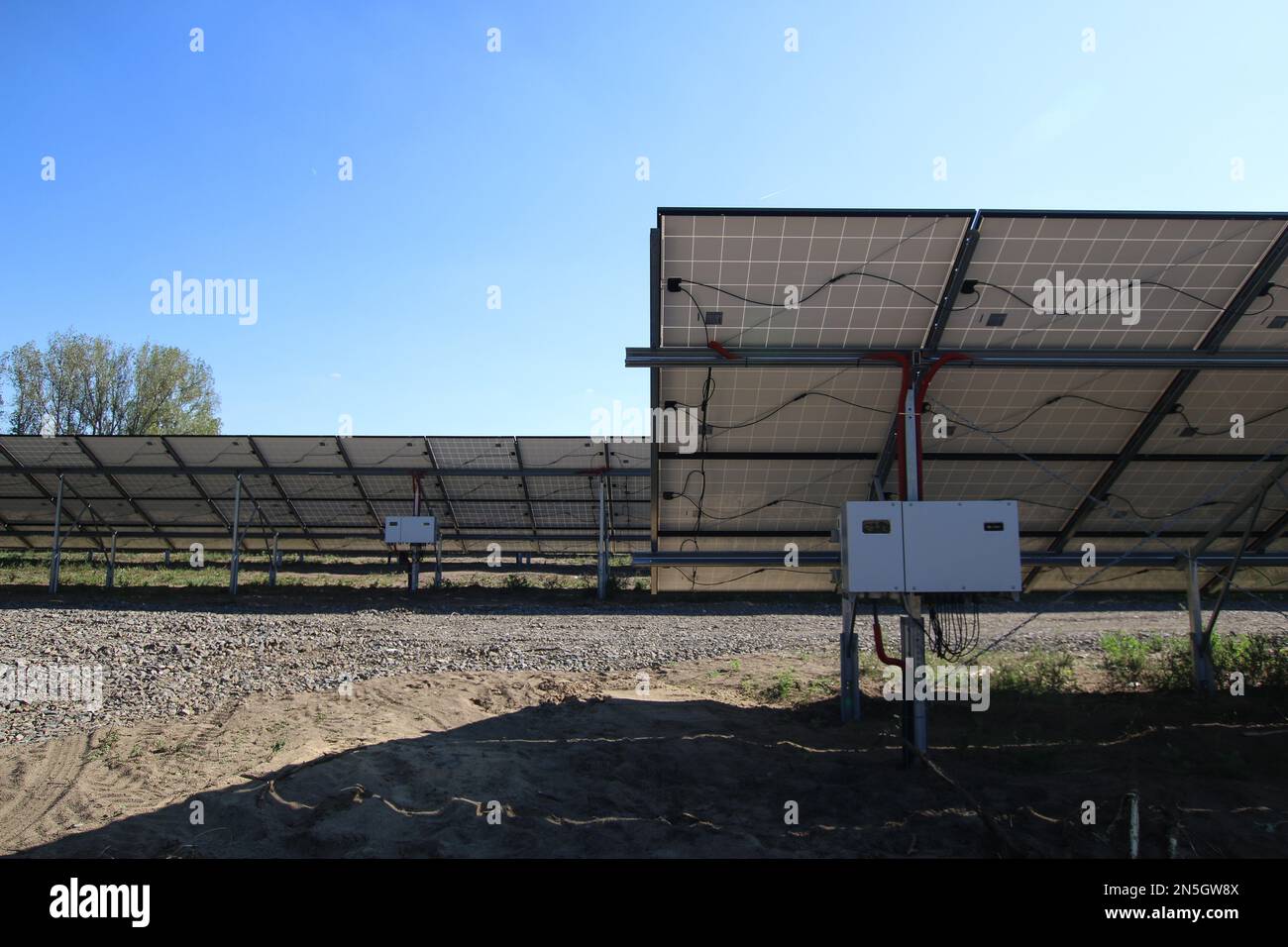 Line of solar power plant panels.  Inverter behind the solar panels. Renewable energy. Solar plant panel for green energy power. Stock Photo