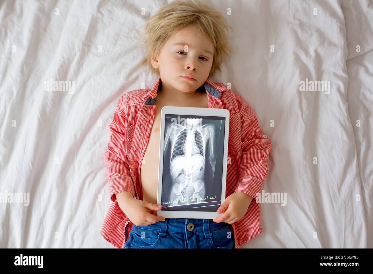 Toddler child, blond boy, holding xray picture on tablet of child body
