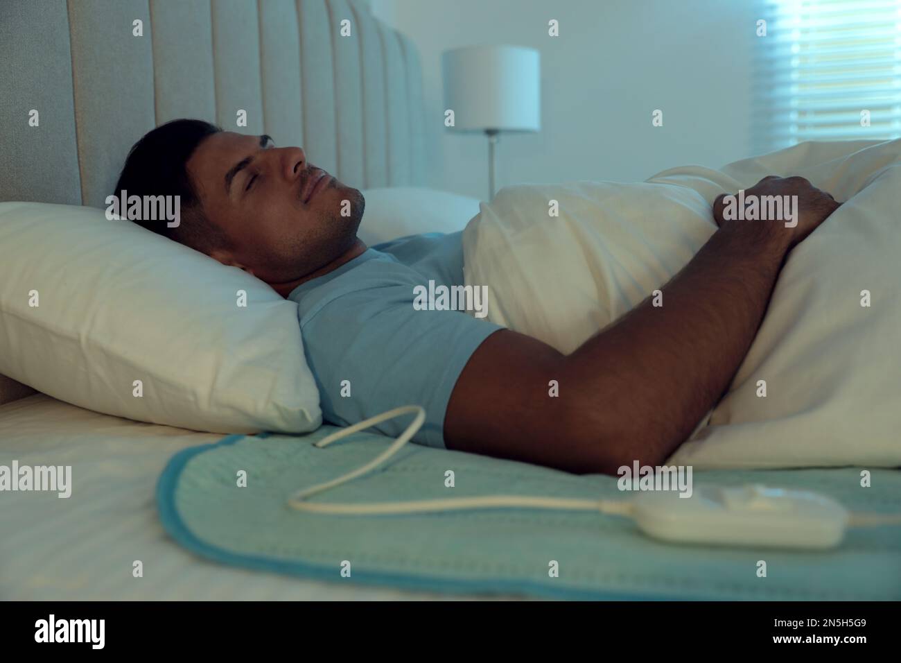 Man sleeping on electric heating pad in bed at night Stock Photo Alamy