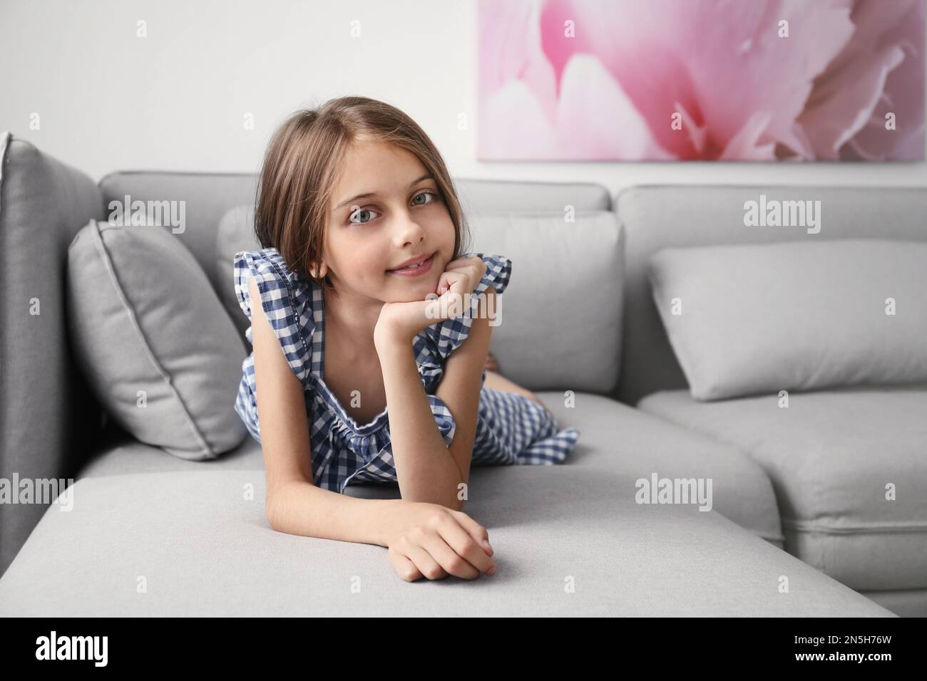 Cute little girl lying on sofa in room Stock Photo - Alamy