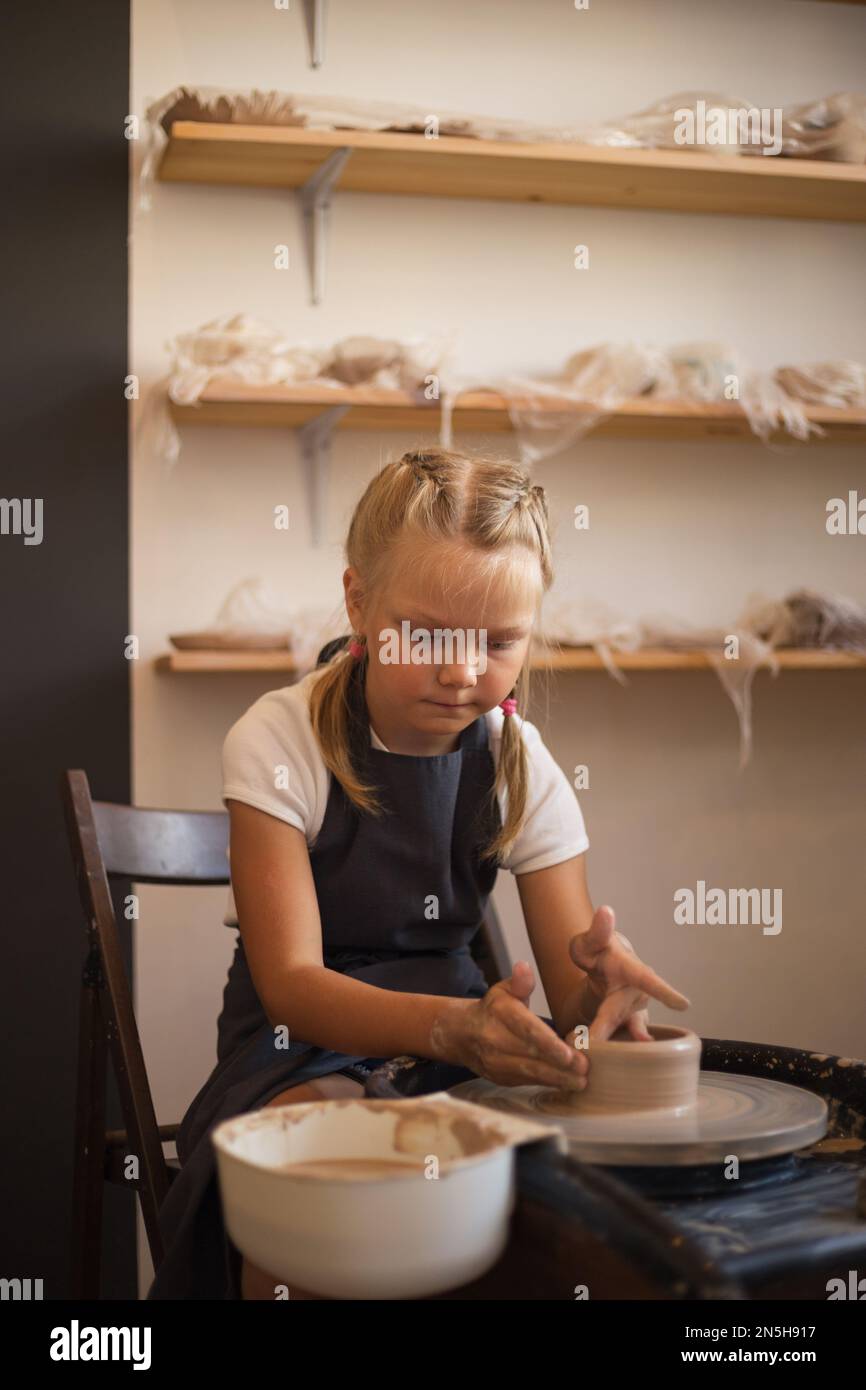 The girl sits at the Potter's wheel and skilled in pottery creat Stock Photo