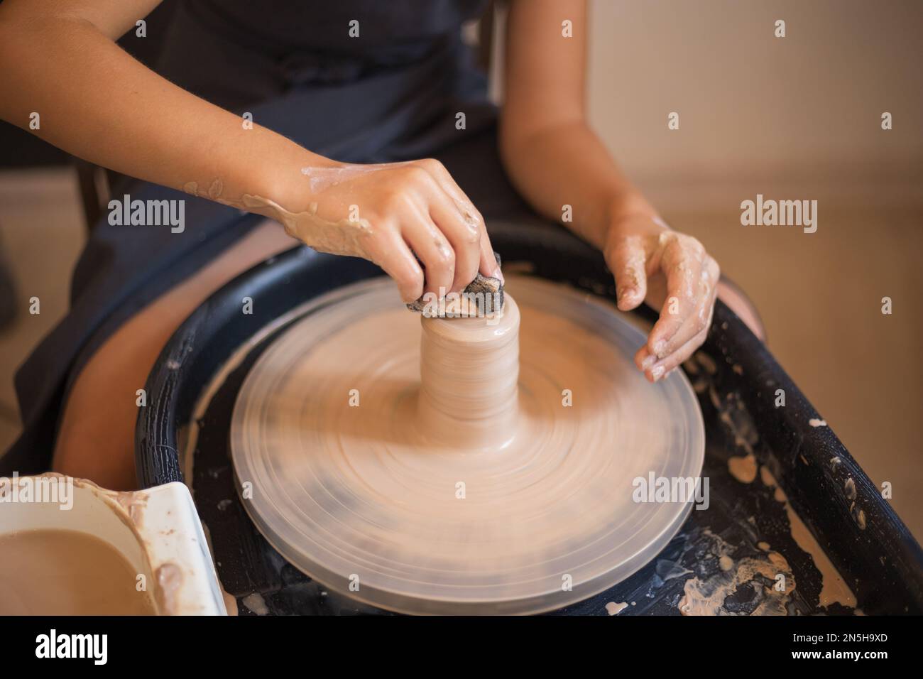 Girl hands working with clay on a Potter's wheel close up. Tradi Stock Photo