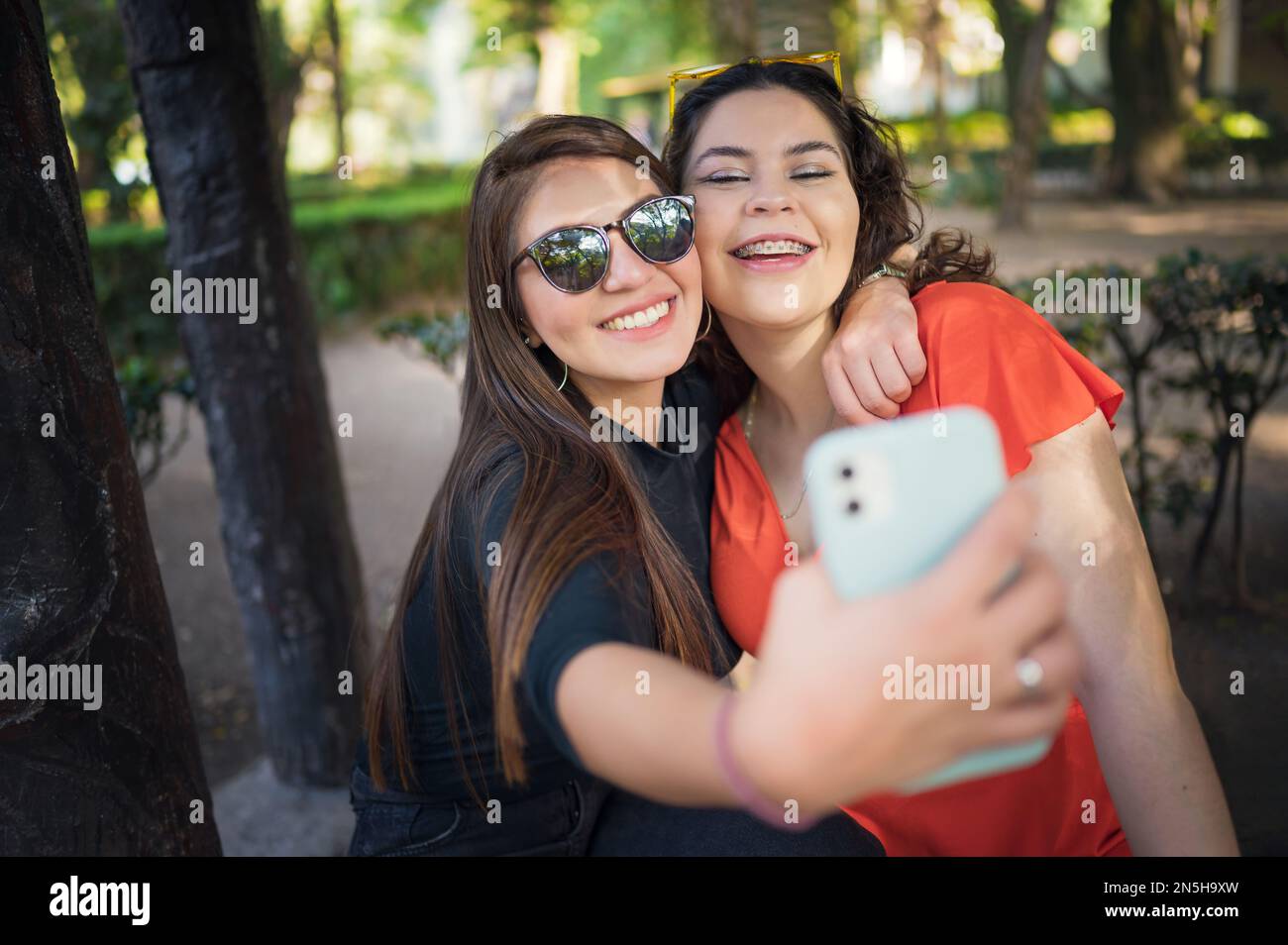 Two young latin female friends walking at the woods Stock Photo