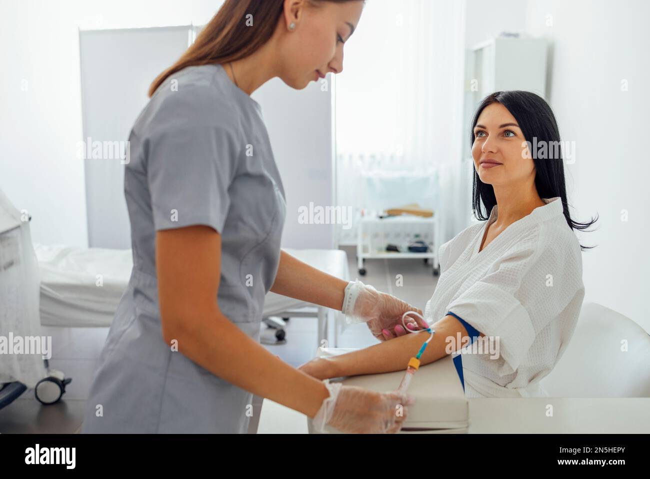 Young woman in a white coat makes medical procedures. A nurse