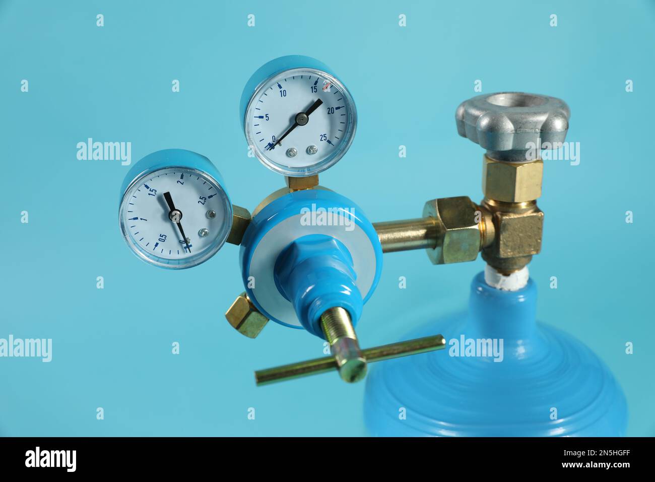 Pressure gauge of medical oxygen tank on light blue background, closeup