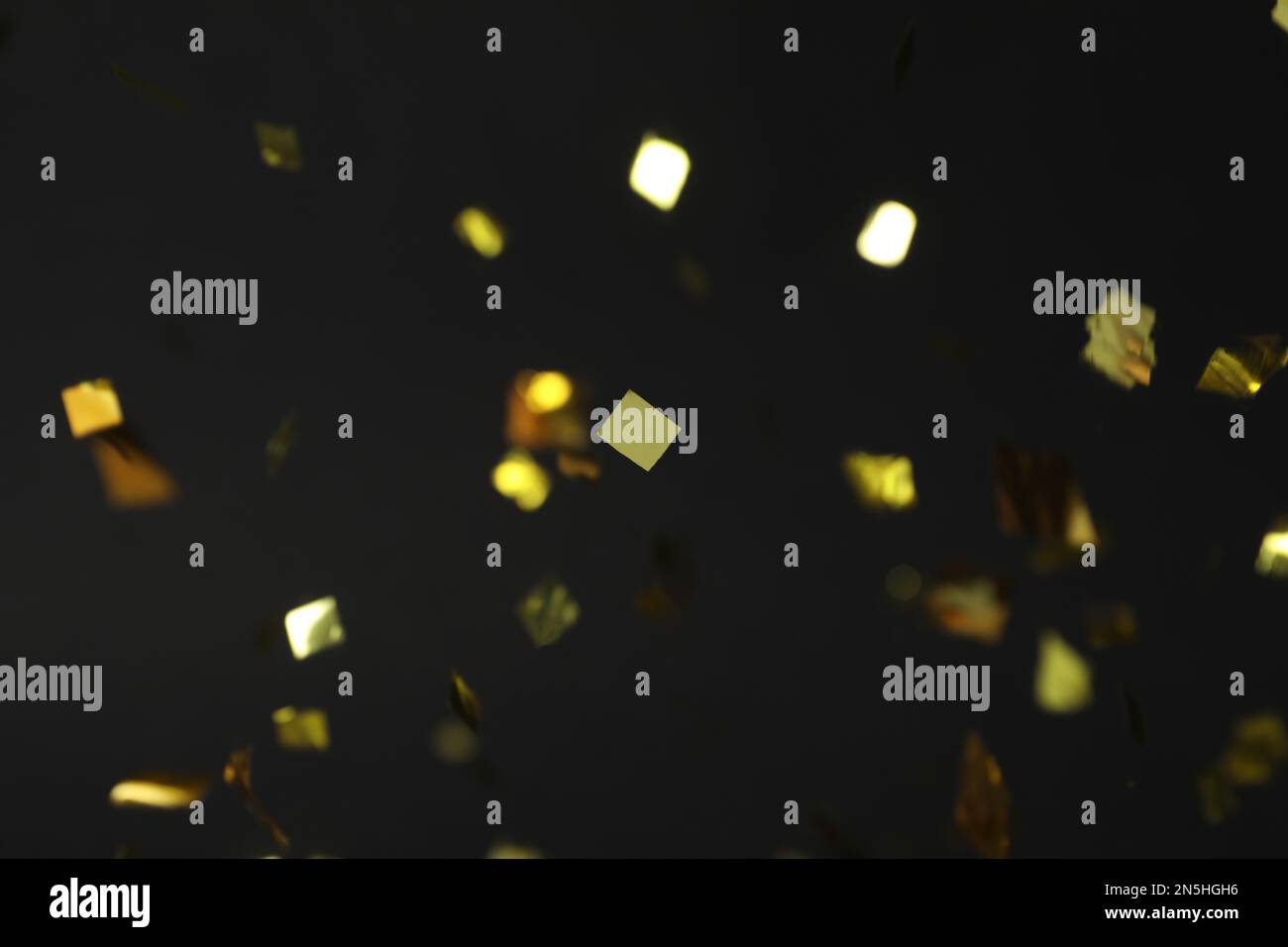 Shiny golden confetti falling down on black background Stock Photo - Alamy