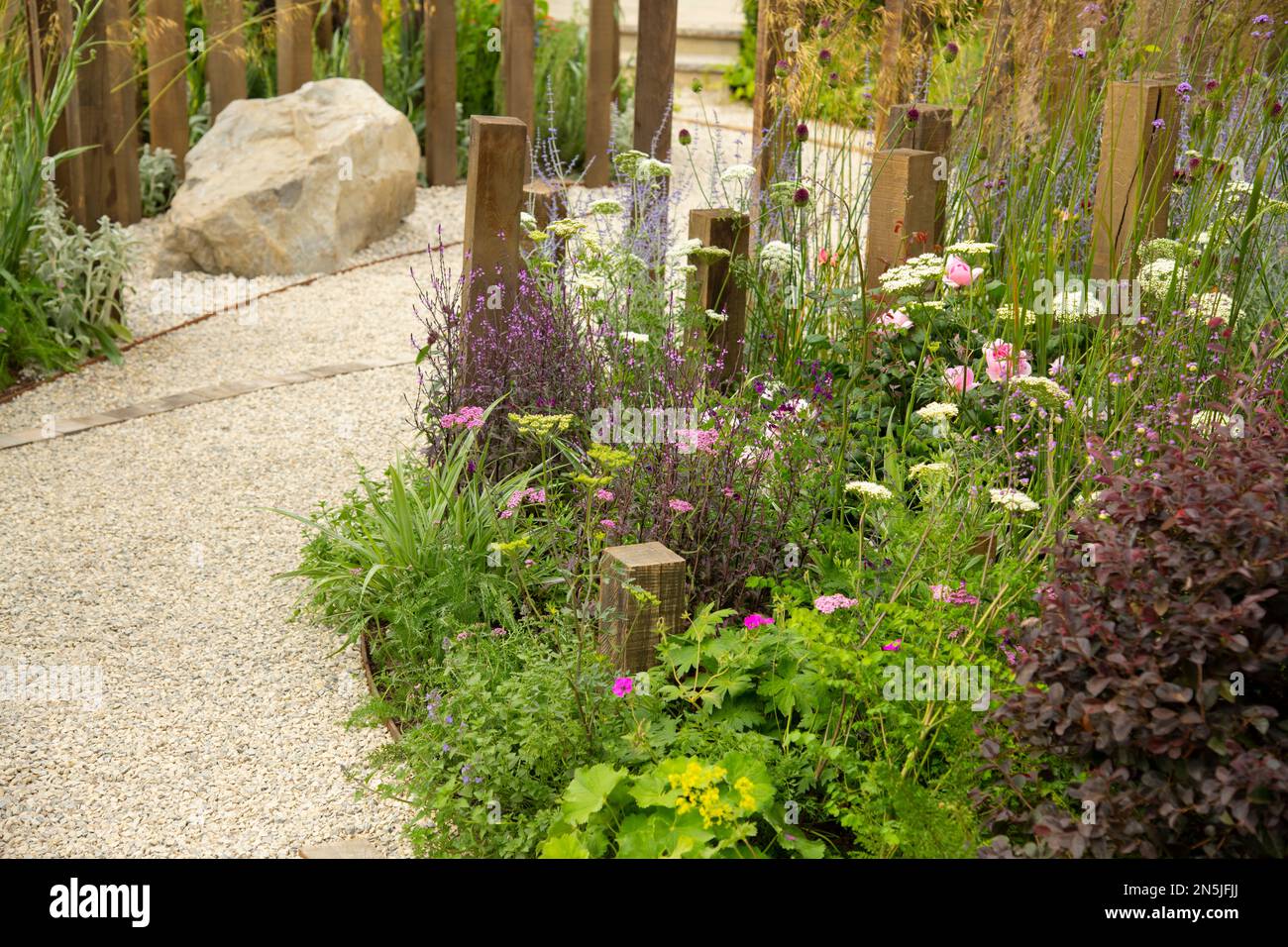 A curved path through borders of mixed perennials in A Journey in Collaboration with Sue Ryder Garden at the Hampton Court Palace Garden Festival 2022 Stock Photo