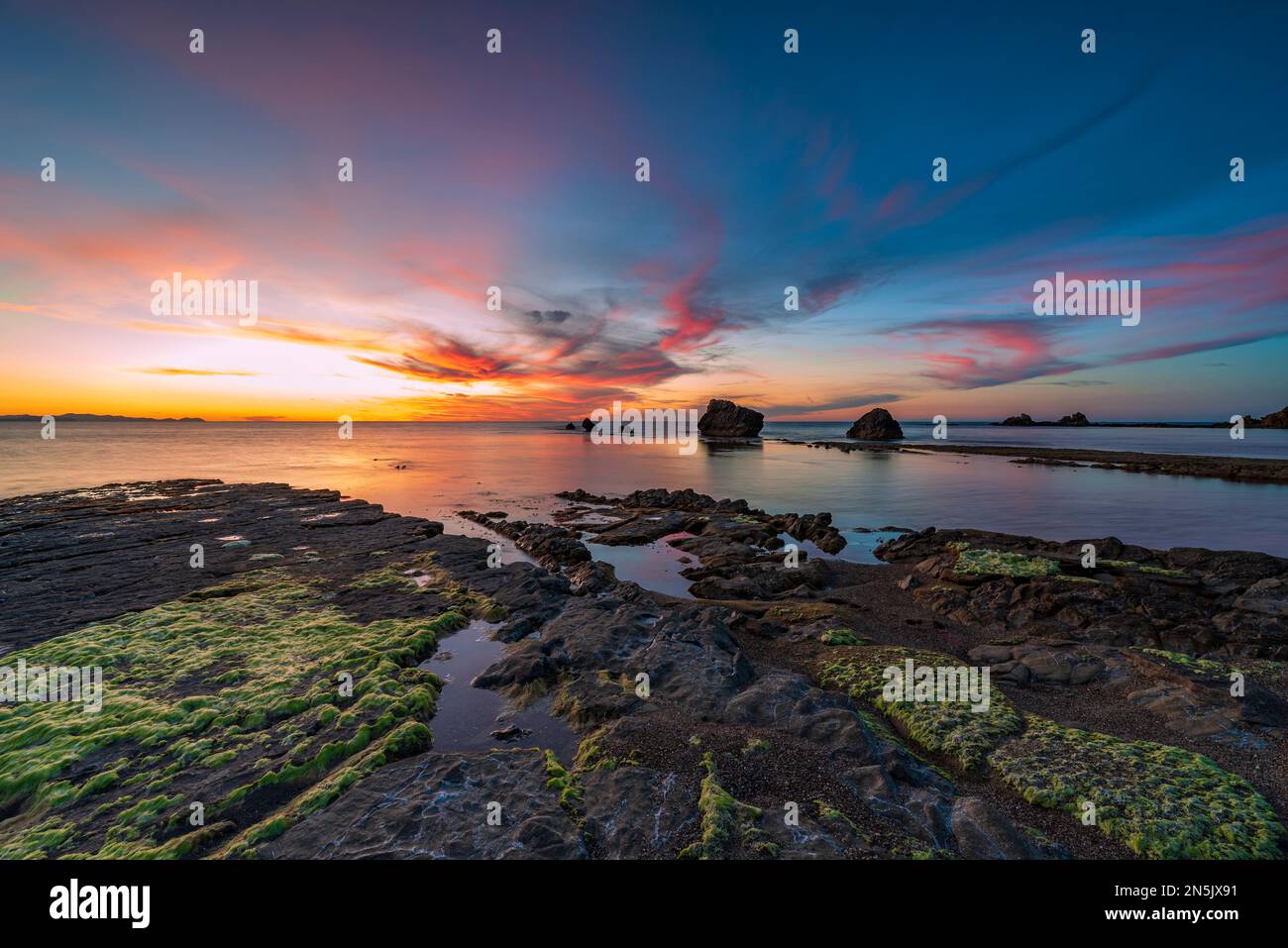 The sun sets behind the rocks of Settefrati beach, Sicily Stock Photo