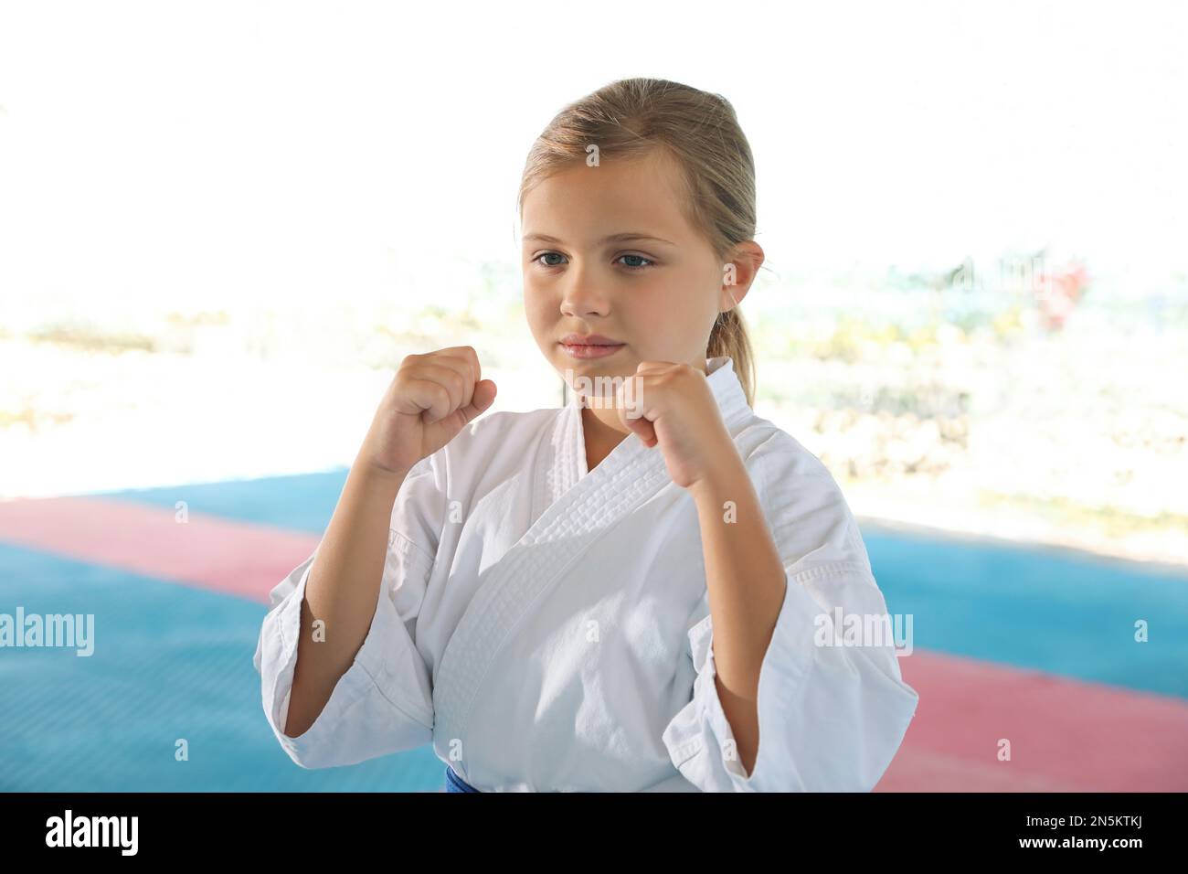 Girl in kimono practicing karate on tatami outdoors Stock Photo